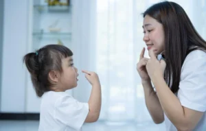 Gambar seorang perempuan sedang memberikan pelajaran berbicara kepada seorang anak