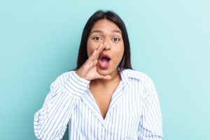 Seorang wanita berbicara dengan penuh semangat sambil mengangkat tangan, menunjukkan ekspresi percaya diri dalam percakapan.