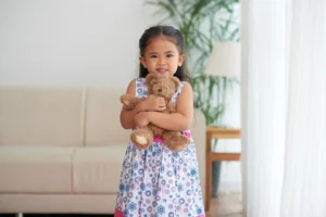 Gambar seorang anak kecil sedang memeluk boneka