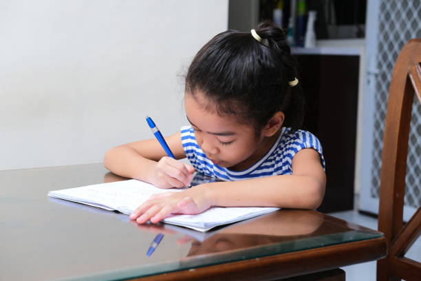 Gambar seorang anak kecil perempuan sedang menulis di buku