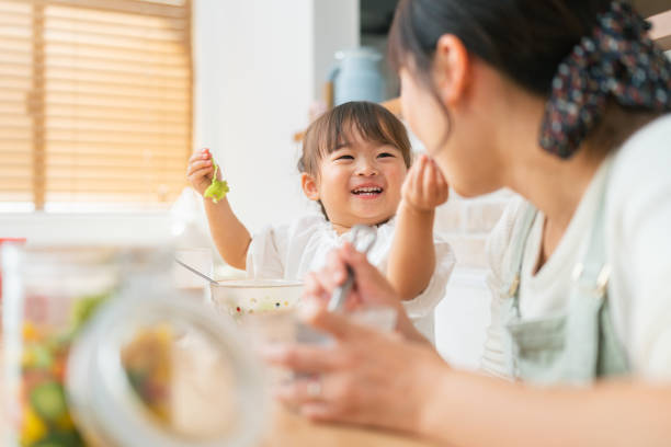 Gambar seorang anak kecil sedang makan bersama ibunya dengan suasana hangat dan penuh kasih di meja makan